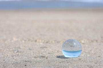 Glass sphere reflecting summer beach and blue sky