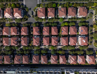 Modern, luxury Housing estate with houses, and villas in rows, beautiful landscaping on sunny, clear morning from top down vertical aerial view. Camera above rooftops landscape format.