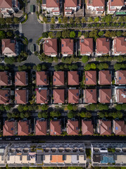 Modern, luxury Housing estate with houses, and villas in rows, beautiful landscaping on sunny, clear morning from top down vertical aerial view. Camera above rooftops vertical format.
