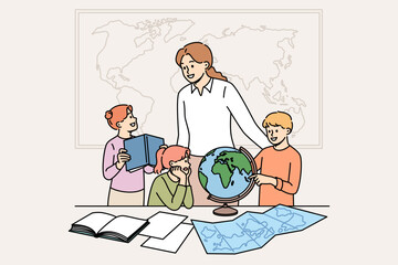 Geography teacher teaches small children using maps and globes or atlases, standing in classroom. Happy schoolchildren rejoice with interest learning new facts during geography lesson © Dzianis Vasilyeu