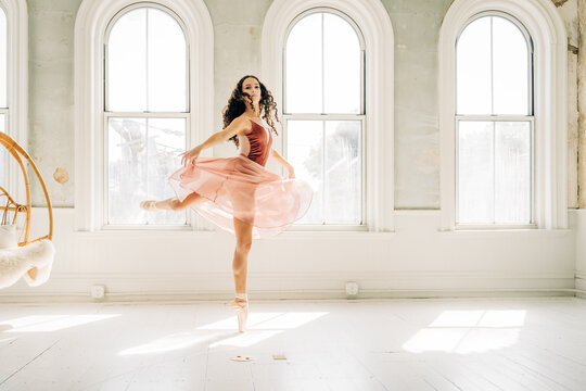 Ballerina gracefully spins on pointe in a softly lit dance studio