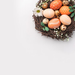 Easter nest with hand-painted eggs and quail eggs on a light background. A rustic spring composition with natural elements, fresh greenery and floral details.