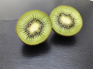 Two kiwi fruit halves on a dark background