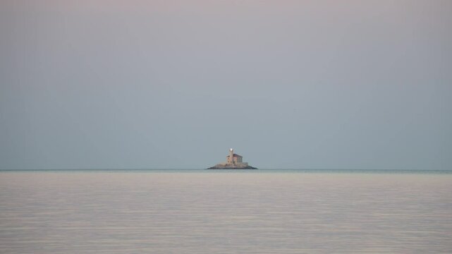 Stone lighthouse Mulo far on the horizon in front of small tourist town of Rogoznica, Croatia