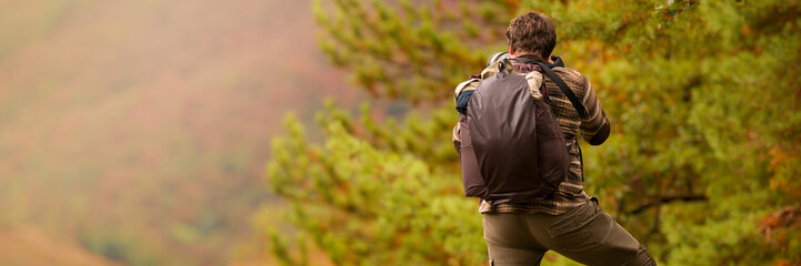 Nature photographer. Young male photographer autumn season outdoors portrait. Back view. Landscape photographer taking photos.