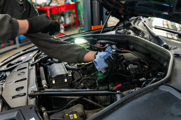 Serviceman checks the oil level in a car engine