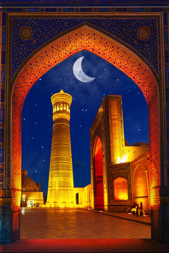 Poi-Kalyan architectural ensemble - minaret, madrasah and mosque in beautiful illumination. Fabulous Arabian night. View through the arch.