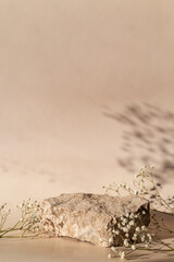 Natural stone podium with gypsophila and shadow on a light beige background.