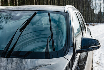 Obraz premium Wipers of dirty car windshield in winter season.