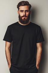 Man with beard in black shirt poses against neutral background