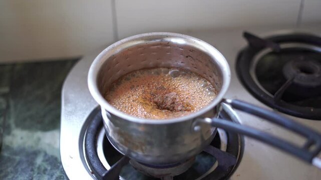 Making masala chai or chai tea in stainless steel pot. Popular indian beverage masala tea or chai .