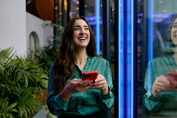 Smiling entrepreneur in a modern office lobby holding a phone