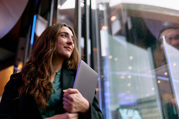 Businesswoman with laptop looking hopeful in modern office building