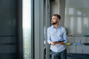 Young man with a tablet in a modern office with high windows