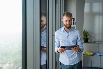 Young man using tablet in modern office with high windows