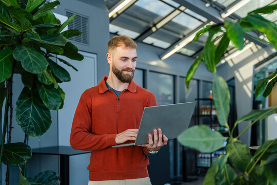 Young man working on a laptop in a green office environment