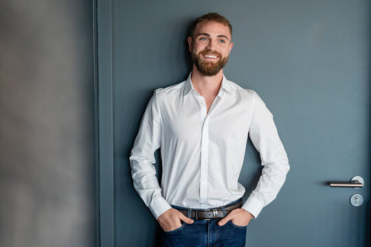 Young man smiling in office portrait wearing white shirt and jeans