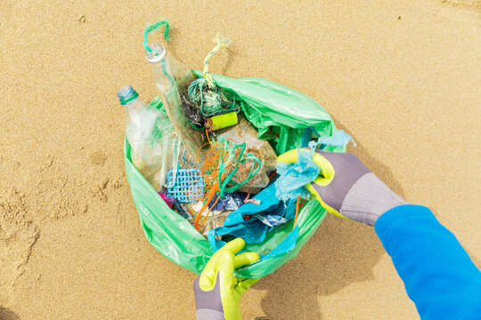 Hands collecting plastic waste on a North Sea beach for environmental protection