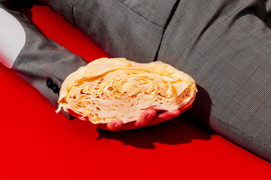 Man in a suit holding half a cabbage on a red background