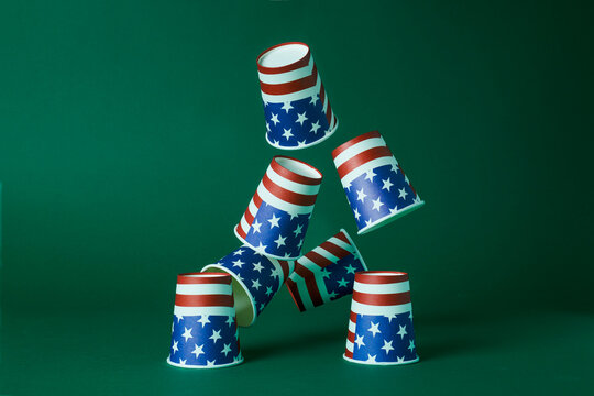 Disposable cups with American flag design stacked in a tower against a green background