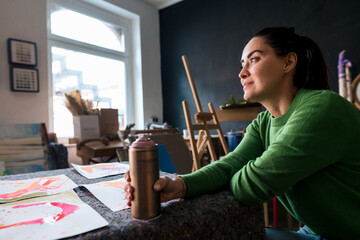 Artist in a creative workspace with art supplies and a spray can