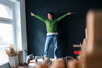 Creative small business owner in a workshop pointing and smiling