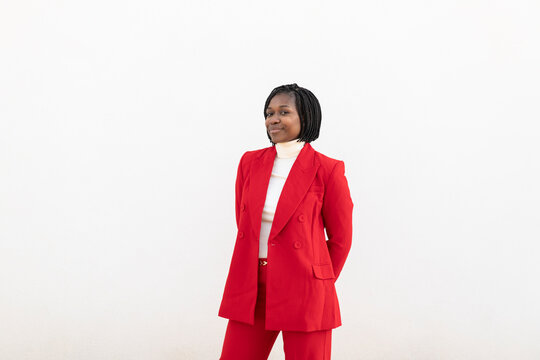Businesswoman in a red suit smiling confidently against a white background