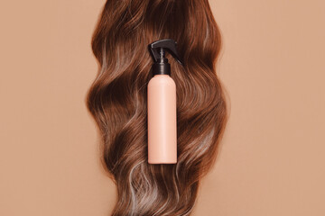 Shampoo bottle on curly brunette hair with brown background