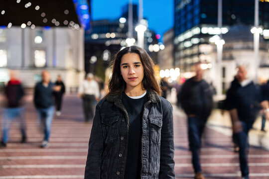 Woman standing in a busy city street during rush hour in the evening