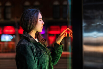 Woman interacting with a bright screen at night in an urban setting