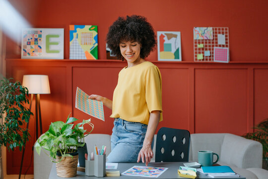 Designer working in a modern studio with colorful illustrations and a plant on the desk