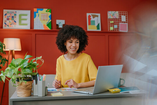 Designer working at a colourful and creative studio using a laptop