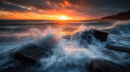 Obraz premium Fiery Sunset Over Dramatic Ocean Waves Crashing on Rocky Shore