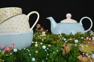 Fairytale garden - three three cups in a stack and blue pot surrounded by a moss and baby's breath....