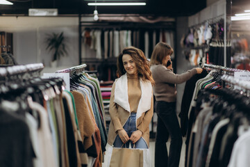 Smiling Woman Shopping in Clothing Store Surrounded by Racks of Colorful Garments