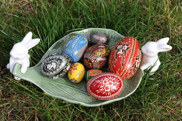Decorative plate with white Easter rabbits and traditional hand-dyed and hand-painted Easter eggs on the green grass in Poland called pisanka or kroszonka or kraszonka