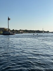 Felucca sailing on Nile River and Nubian boys on surfboard in a sunny afternoon at Aswan, Egypt