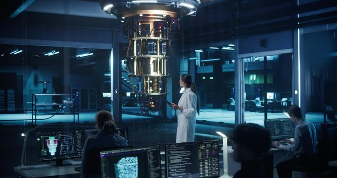 Female Engineer Working on Quantum Computer Hardware, Using Tablet Computer to Access Technical Specifications and Control Processor Parameters. Group of Developers Work on AI Behind a Desk