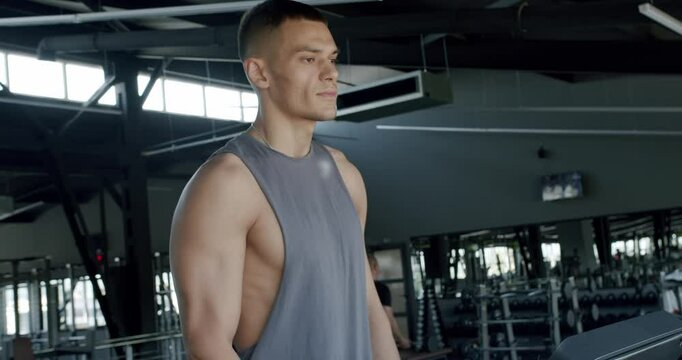 A young, athletic man is joggin on a treadmill in a well-equipped, spacious gym. He appears focused and fit, perfect for fitness-themed content. Focused Young Man on Treadmill in Modern Gym Setting