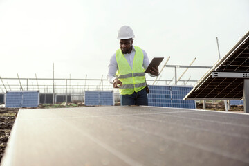 Multicultural inspector with tablet examining solar panels.
