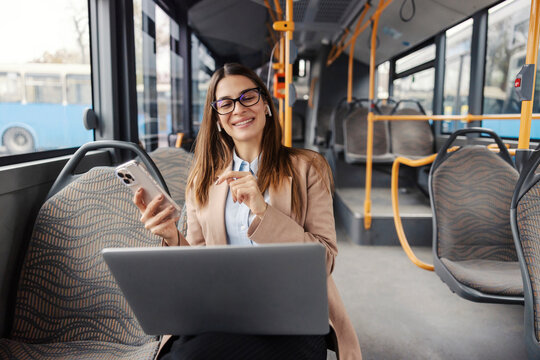 Portrait of young chic woman riding city bus and using cutting edge technologies.