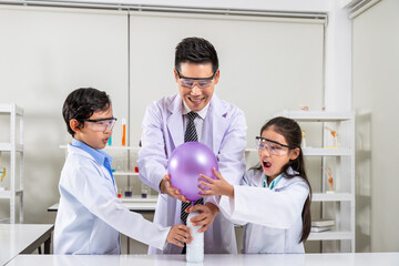 Young scientists in laboratory &ndash; Asian kids and teacher conducting balloon inflation experiment with chemical reaction