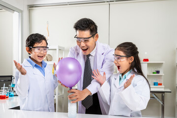 Young scientists in laboratory – Asian kids and teacher excitedly conducting balloon inflation...