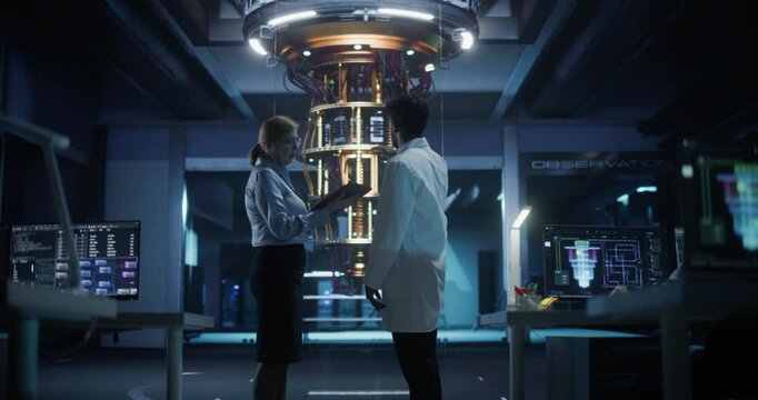 Engineers Having a Conversation About Developing Technology for a Powerful Quantum Processor. Diverse Male and Female Developers Working on Tablet Computer in a Research Facility. Cinematic Low Angle