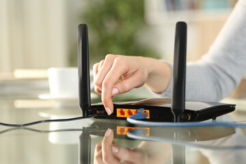 Woman hand reseting or turning on modem at home