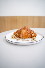Indulgently Delicious Croissant Found Upon a Plate Enhanced with Luxurious Caramel Drizzle