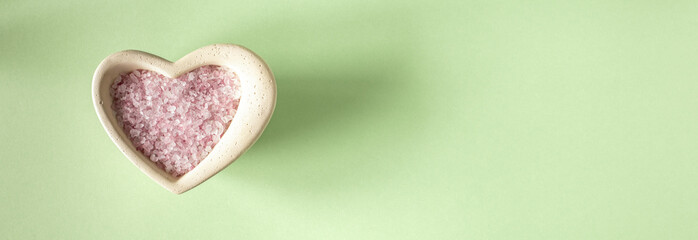 Pink sea salt for cosmetic procedures on a light green background. The banner.