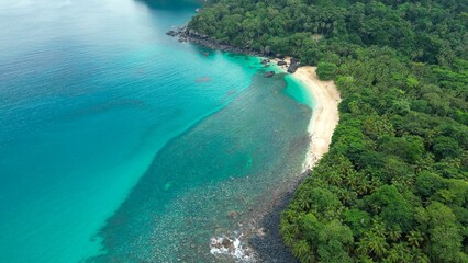 View of a tropical beach with turquoise waters and lush green forest in Sao Tome and Principe.