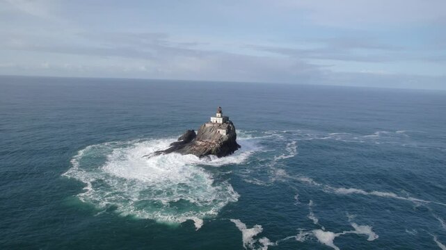 Parallax drone shot of Tillamook Rock Light lighthouse with waves crashing during the day in North Pacific Ocean, northern Oregon Coast, USA