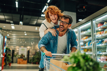 Happy couple having fun while shopping in supermarket